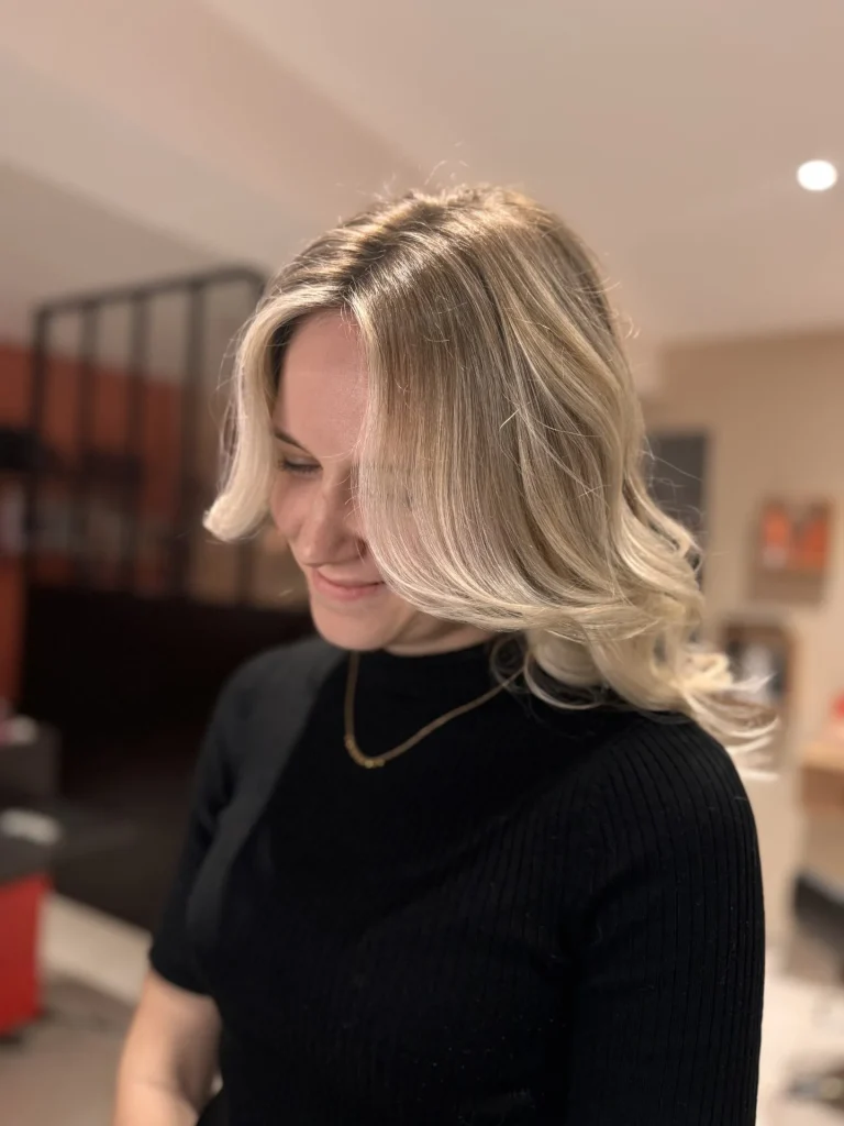 Femme souriante avec des cheveux blonds ondulés.