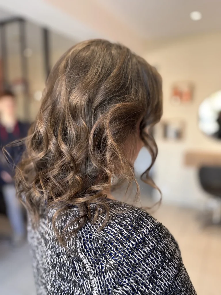 Cheveux bouclés marron coiffure élégante salon